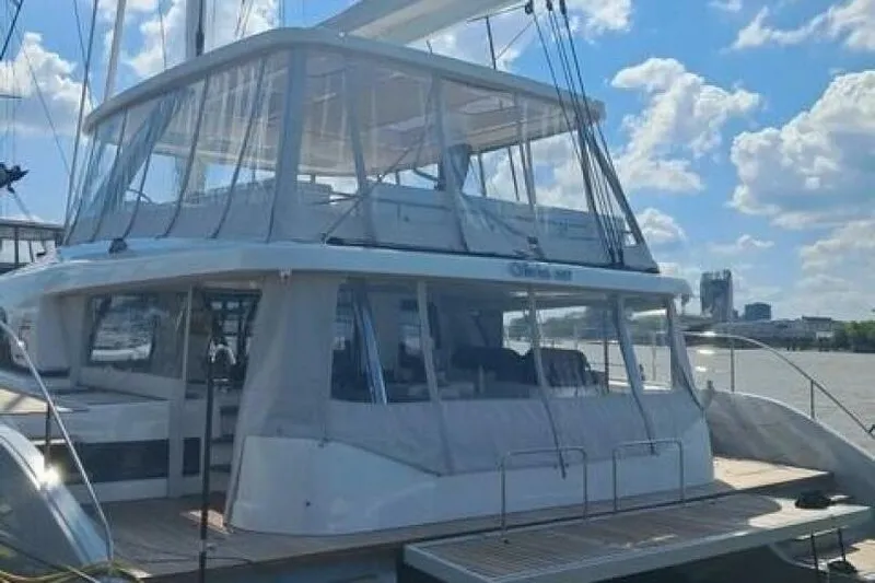 Olivia 007 Yacht Photos Pics 2025 Lagoon 65 yacht with enclosed deck, docked under a bright blue sky.