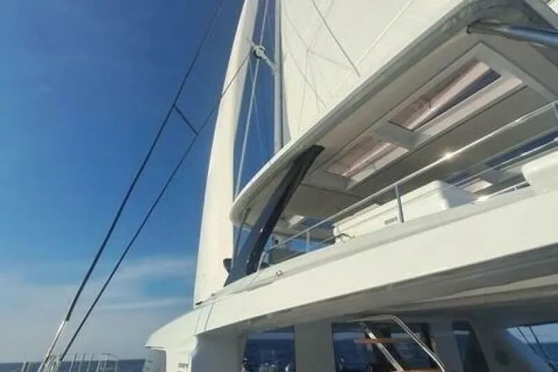 Olivia 007 Yacht Photos Pics 2025 Lagoon 65 yacht with sails, under a clear blue sky.