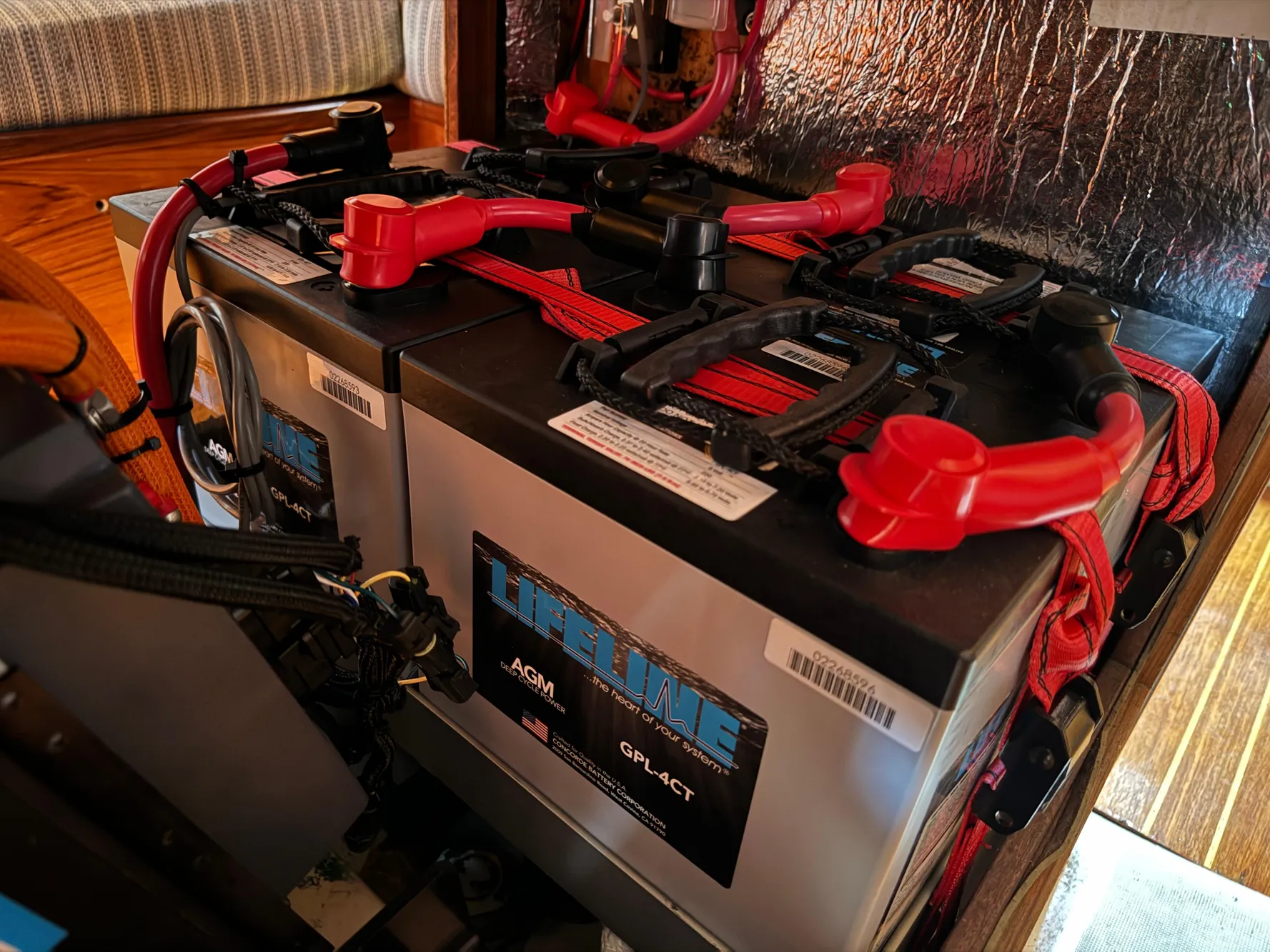 Battery setup inside a 1988 Beneteau First Class 12 sailboat, featuring red cables and connectors.