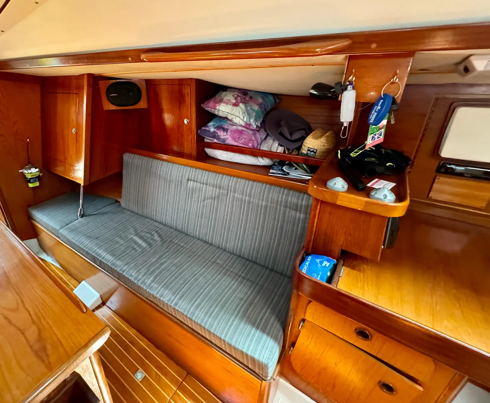 Interior of 1988 Beneteau First Class 12 sailboat, featuring wooden cabinetry and a cushioned bench.