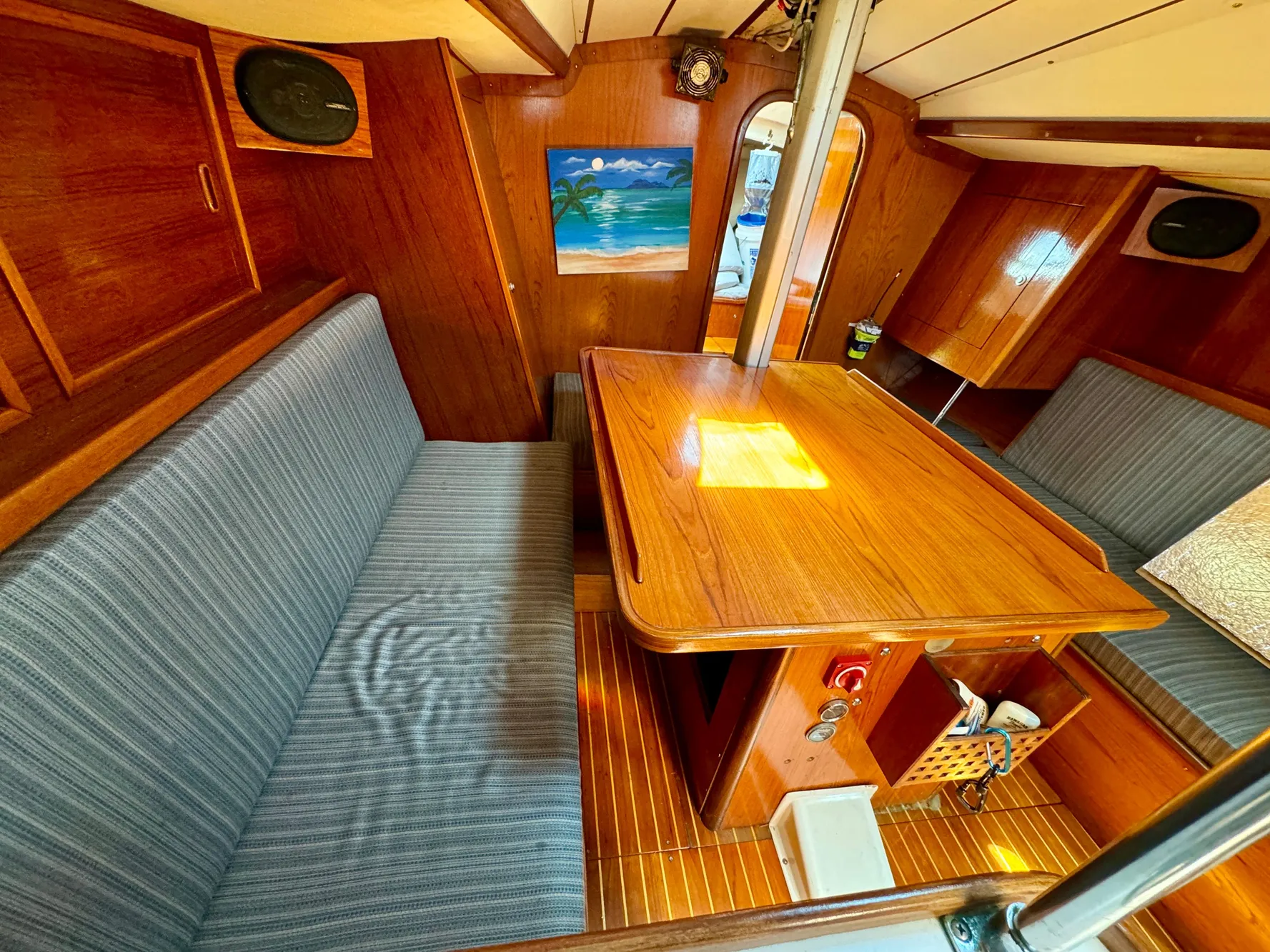 1988 Beneteau First Class 12 yacht interior with wooden table, striped seating, and nautical decor.