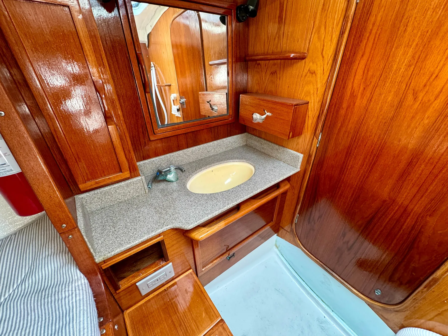 Wooden interior of 1988 Beneteau First Class 12 yacht with sink and mirror.