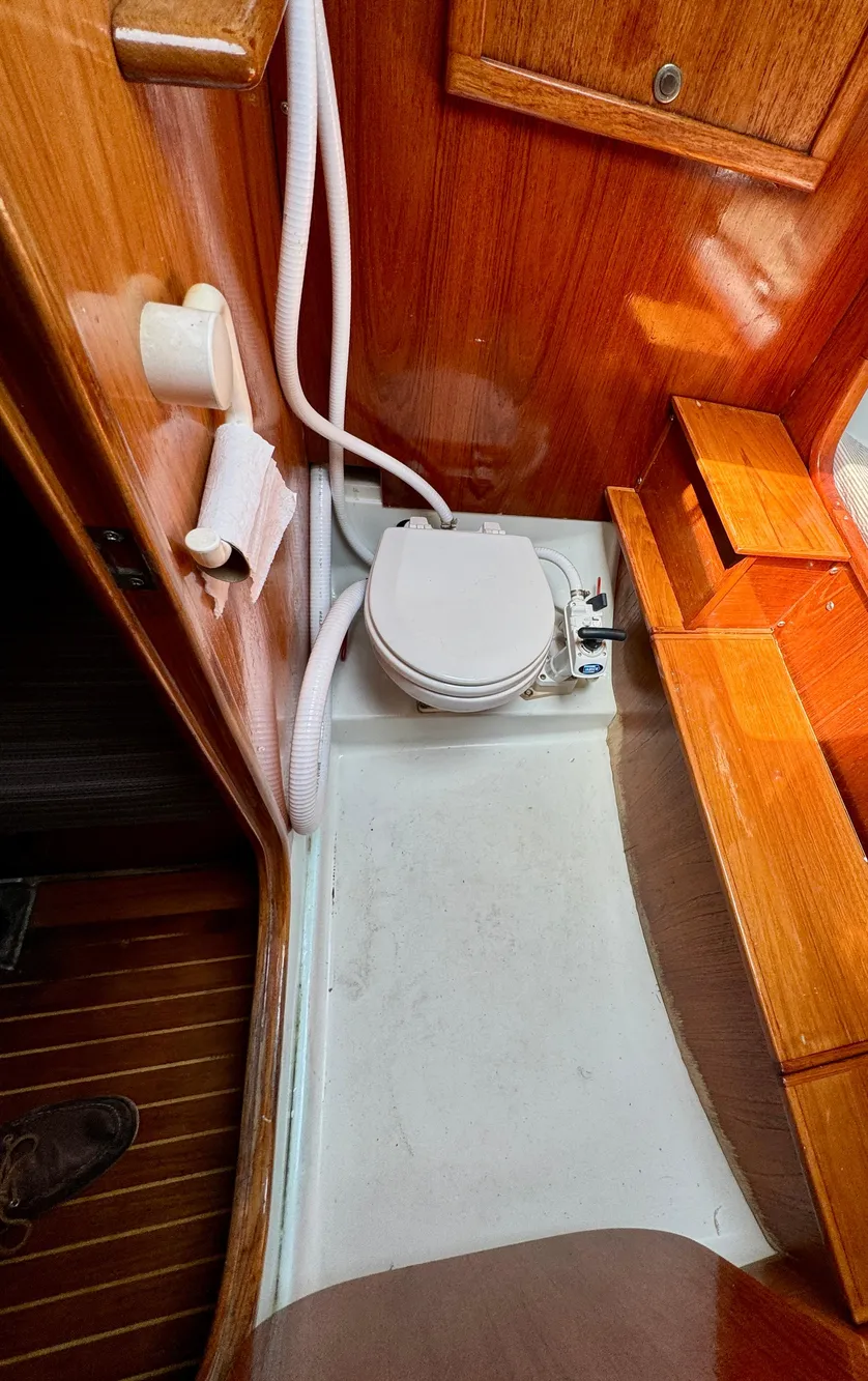 1988 Beneteau First Class 12 yacht bathroom with wooden interior and compact toilet.