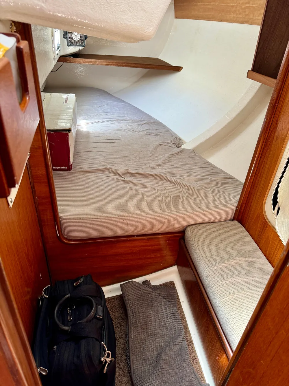 Cozy cabin interior of 1988 Beneteau First Class 12 sailboat with wooden accents and bedding.