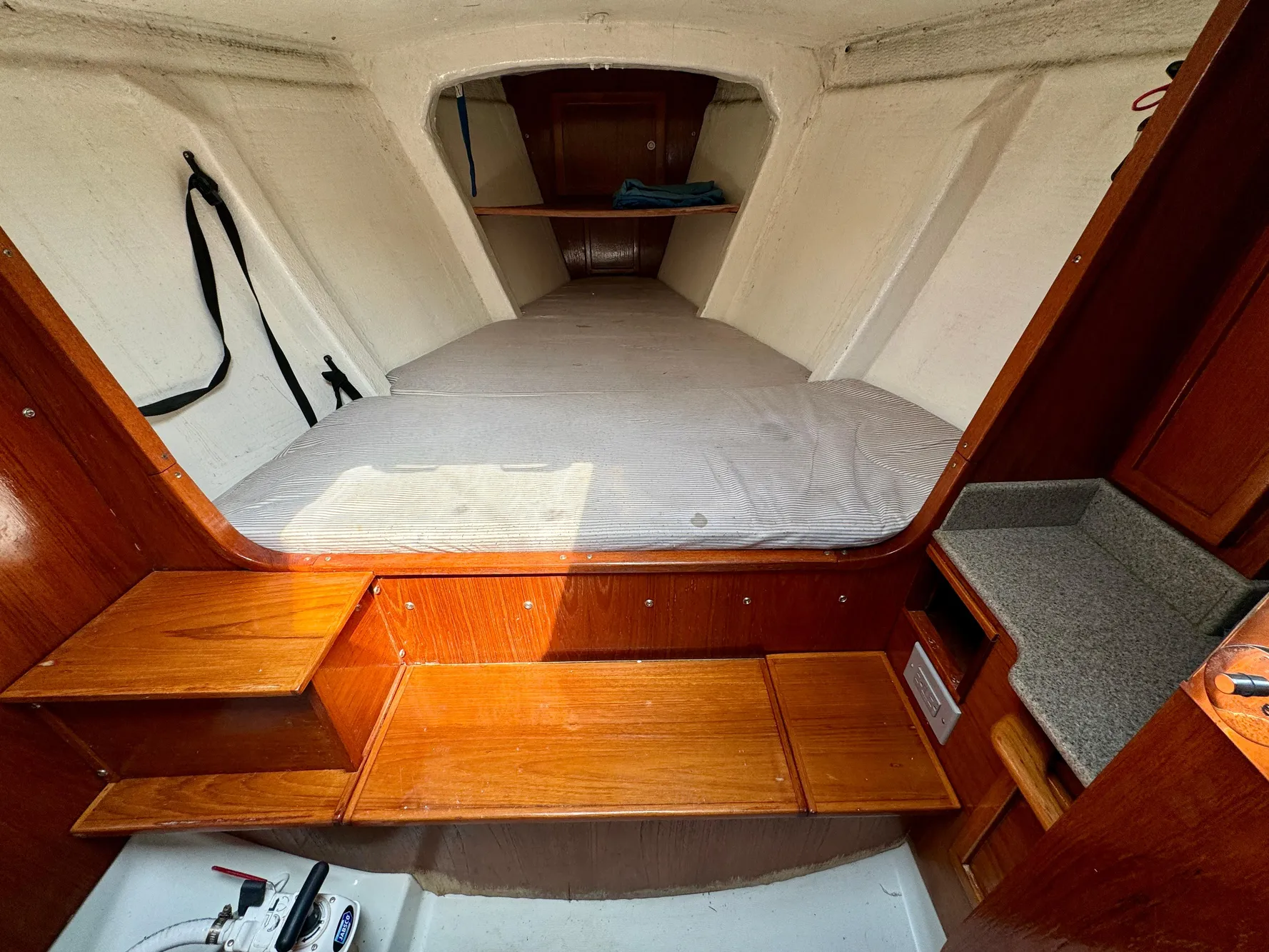 Interior of 1988 Beneteau First Class 12 sailboat with wooden steps and cozy sleeping area.