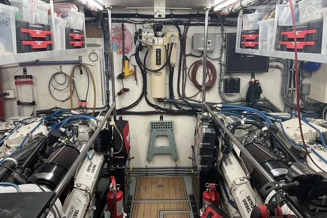 Moor River Yacht Photos Pics Engine room of a 1997 Hatteras 70 Sport Deck Motor Yacht, featuring organized equipment and machinery.