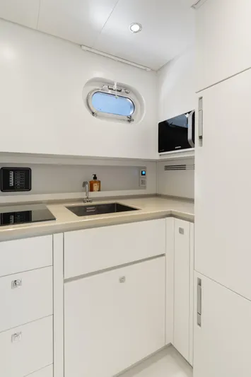 Yours Yacht Photos Pics Modern yacht kitchen interior with sleek white cabinetry, stainless steel sink, and compact appliances.