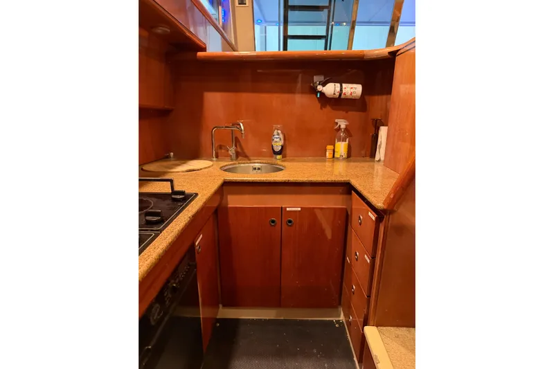  Yacht Photos Pics Compact kitchen area in a 1994 Ferretti Yachts 185 Fly, featuring wooden cabinetry and countertop.