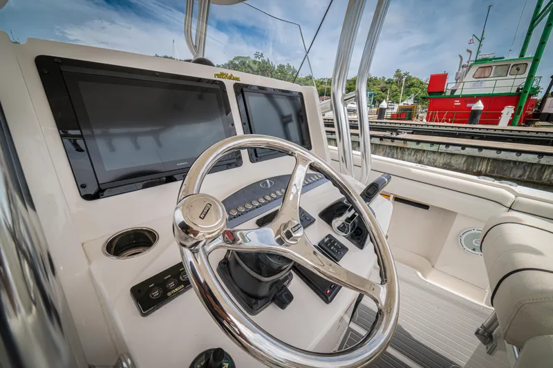 Half Nelson Yacht Photos Pics Steering wheel and dashboard of a 2016 Jupiter HFS boat, docked near a red vessel.