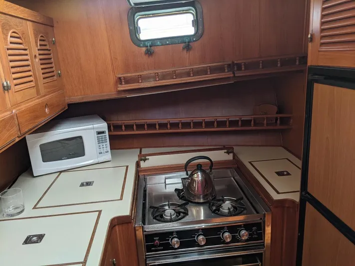 Blue Yacht Photos Pics 1987 Albin Double Cabin kitchen with stove, microwave, and wooden cabinetry.