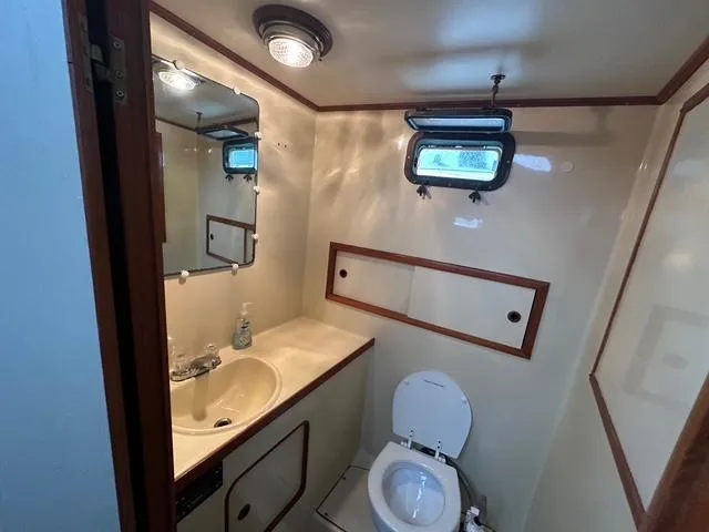 Blue Yacht Photos Pics 1987 Albin Double Cabin bathroom with sink, toilet, mirror, and porthole window.