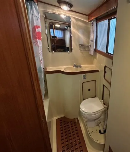 Blue Yacht Photos Pics 1987 Albin Double Cabin bathroom with sink, toilet, mirror, and shower curtain.