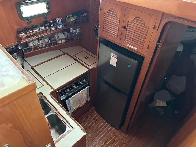 Blue Yacht Photos Pics 1987 Albin Double Cabin kitchen with wooden cabinets, stove, and refrigerator.