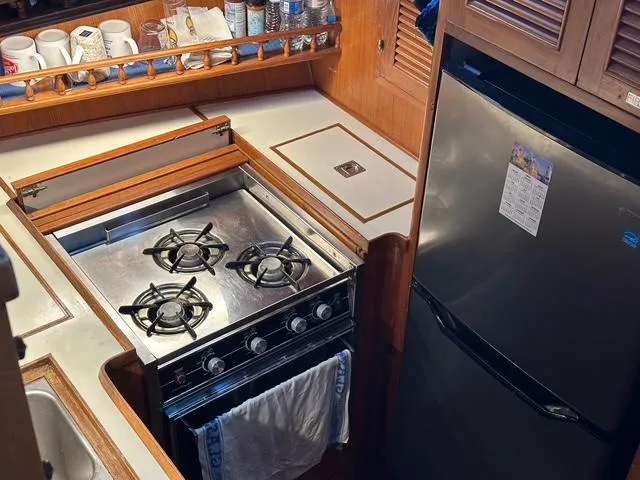 Blue Yacht Photos Pics 1987 Albin Double Cabin kitchen with stove, fridge, and storage shelves.