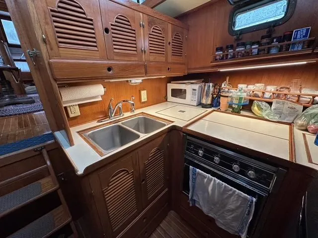 Blue Yacht Photos Pics 1987 Albin Double Cabin kitchen with wooden cabinets, dual sink, stove, and microwave.