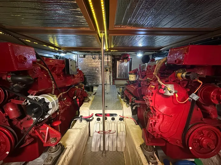 Blue Yacht Photos Pics Engine room of a 1987 Albin Double Cabin boat with red engines and metallic ceiling.