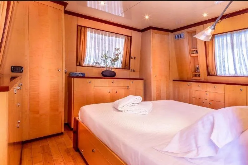Clara One Yacht Photos Pics Luxurious bedroom interior on a 1961 Custom 90 yacht, featuring wood paneling and elegant decor.