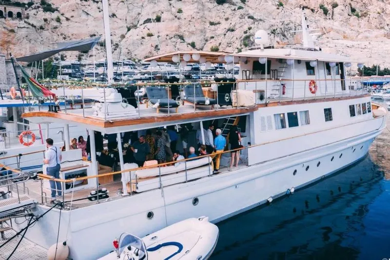 Clara One Yacht Photos Pics Luxurious 1961 Custom 90 yacht docked, hosting a lively gathering with scenic coastal backdrop.