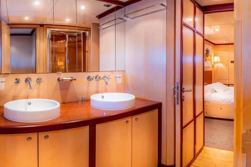 Clara One Yacht Photos Pics Luxurious yacht bathroom with dual sinks, wooden cabinetry, and adjacent bedroom, Custom 90, 1961.