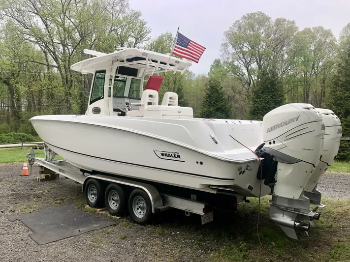  Yacht Photos Pics 2016 Boston Whaler OUTRAGE boat on trailer with American flag, parked outdoors.