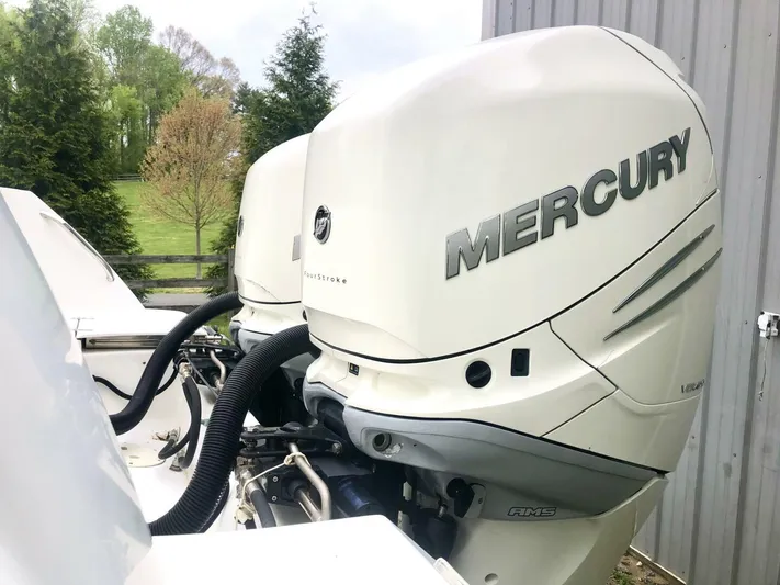  Yacht Photos Pics 2016 Boston Whaler OUTRAGE with twin Mercury outboard engines, parked near a green landscape.