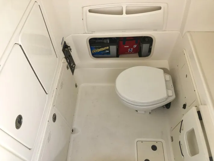  Yacht Photos Pics 2016 Boston Whaler OUTRAGE boat interior with compact marine toilet and storage compartments.