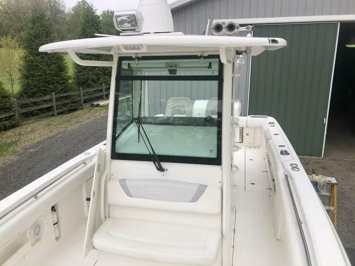  Yacht Photos Pics 2016 Boston Whaler OUTRAGE boat with white deck and cabin, parked near a green building.