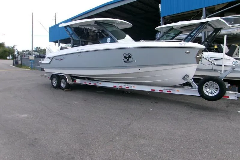  Yacht Photos Pics 2026 Monterey Elite 30 OB boat on trailer outside a blue-roofed building.