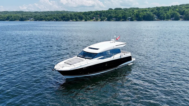  Yacht Photos Pics 2023 Prestige 520S yacht cruising on a serene lake with lush green shoreline.