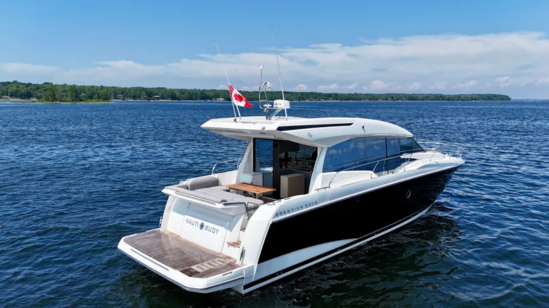 Yacht Photos Pics 2023 Prestige 520S yacht cruising on a serene lake under a clear blue sky.