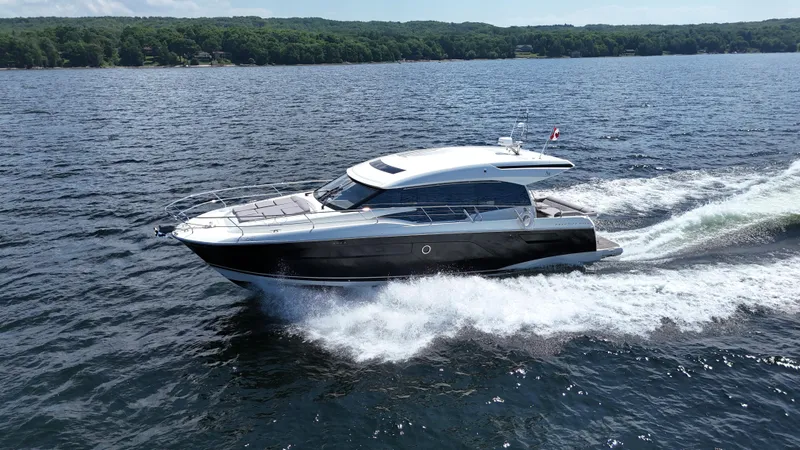  Yacht Photos Pics 2023 Prestige 520S yacht cruising on a lake with lush green shoreline.