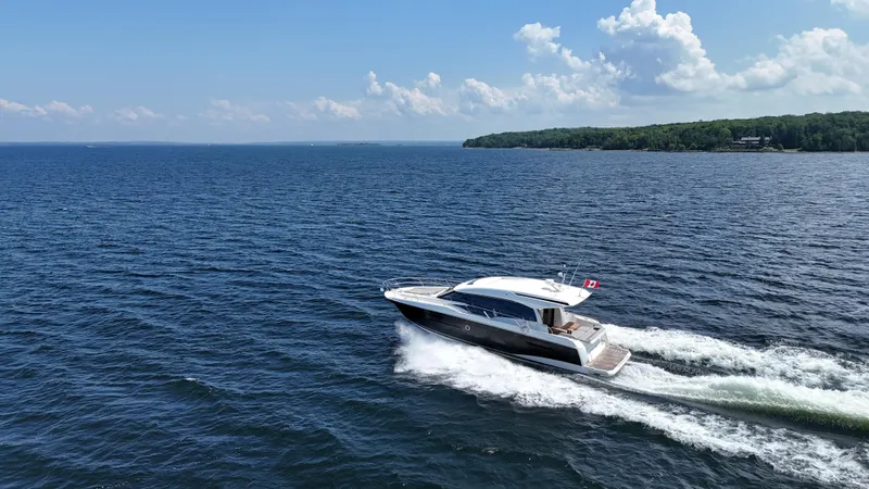  Yacht Photos Pics 2023 Prestige 520S yacht cruising on a serene lake under a clear blue sky.