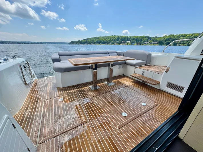  Yacht Photos Pics Luxurious 2023 Prestige 520S yacht deck with seating, table, and scenic water view.