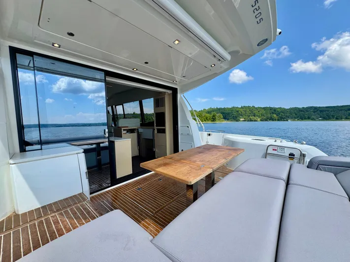  Yacht Photos Pics Luxurious 2023 Prestige 520S yacht interior with wooden table, plush seating, and scenic lake view.