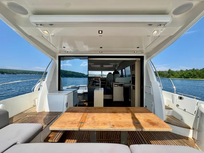  Yacht Photos Pics Luxurious 2023 Prestige 520S yacht interior with wooden table, open deck, and scenic water view.