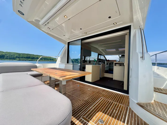  Yacht Photos Pics Luxurious 2023 Prestige 520S yacht interior with open deck, wooden table, and scenic water view.