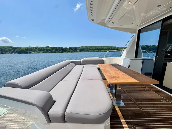  Yacht Photos Pics Luxury 2023 Prestige 520S yacht with spacious deck seating and wooden table, overlooking serene waters.