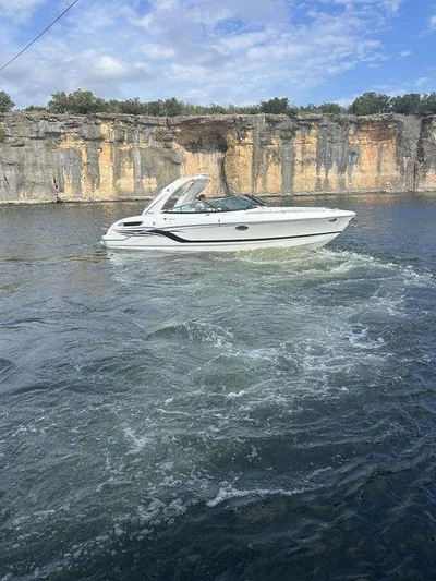  Yacht Photos Pics 2025 Formula 290 Bowrider cruising on a scenic lake with rocky cliffs.