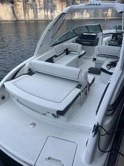  Yacht Photos Pics 2025 Formula 290 Bowrider boat with spacious seating, docked by a rocky shoreline.