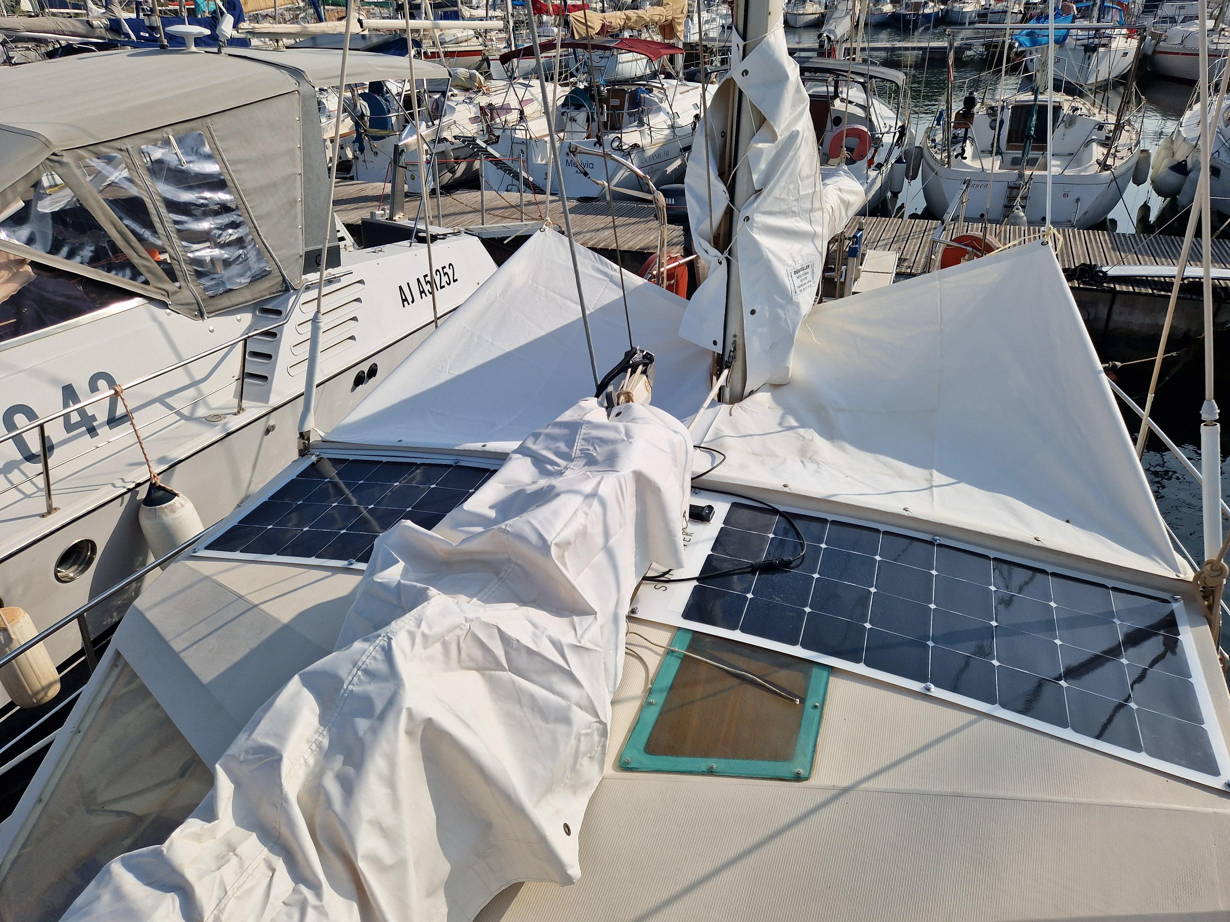 1982 Amel Maramu sailboat with solar panels docked in a marina.