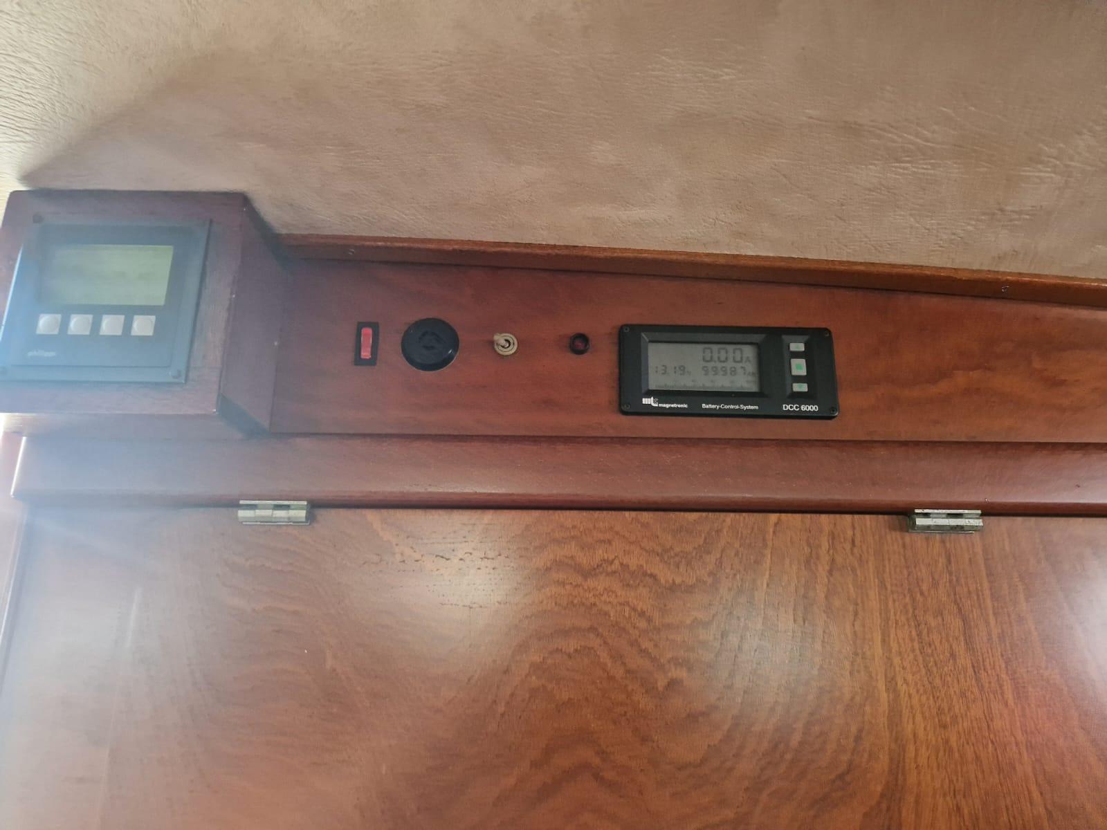 Control panel inside 1982 Amel Maramu yacht, featuring digital displays and wooden finish.