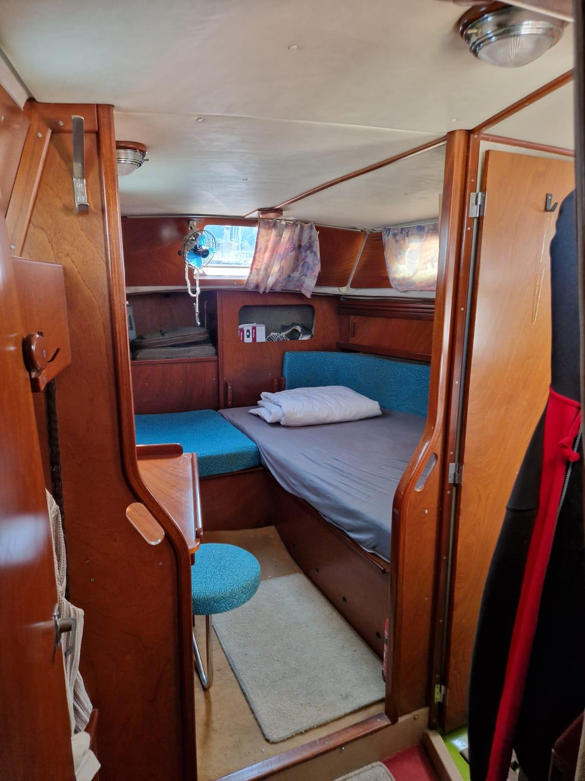 Cozy cabin interior of 1982 Amel Maramu sailboat with wooden furnishings and blue upholstery.