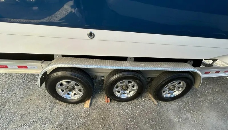  Yacht Photos Pics Trailer with triple axle wheels for 2005 Cobalt 343 boat on gravel surface.