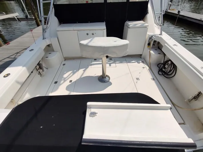 Reel Time Yacht Photos Pics 2005 Rampage 38 Express boat deck with seating and storage, docked by the water.