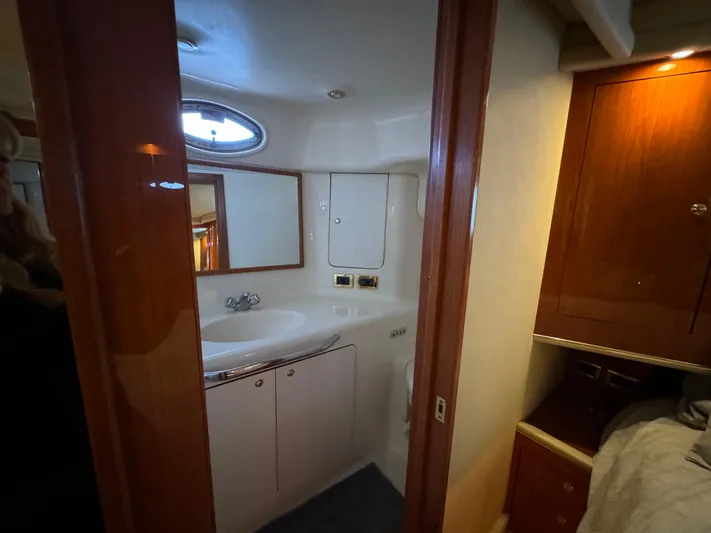 Fathom This Yacht Photos Pics 2001 Sea Ray 420 Aft Cabin bathroom with sink, mirror, and wooden cabinetry.