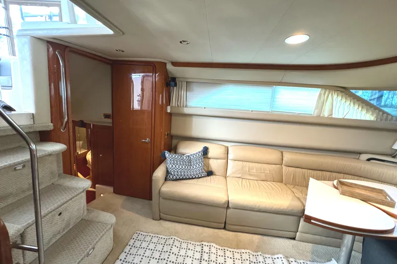 Fathom This Yacht Photos Pics Interior of 2001 Sea Ray 420 Aft Cabin with beige sofa and wooden accents.