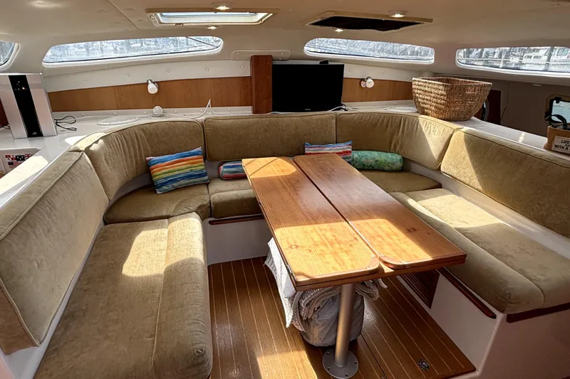 Serenity Yacht Photos Pics Luxurious interior of 2003 PDQ 36 Capella catamaran with cozy seating and wooden table.
