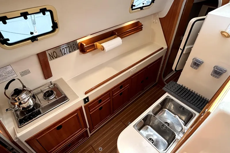 Serenity Yacht Photos Pics Interior of 2003 PDQ 36 Capella yacht kitchen with stove, sink, and wooden cabinetry.