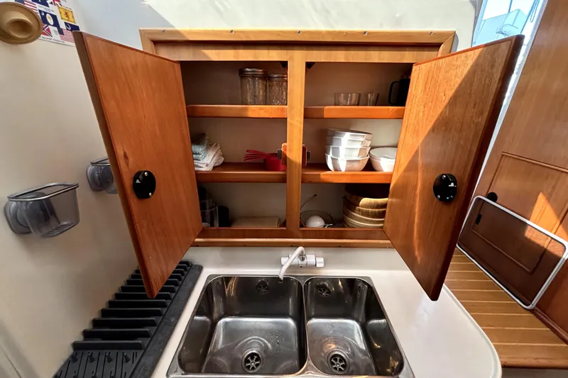 Serenity Yacht Photos Pics Kitchen area of 2003 PDQ 36 Capella with open wooden cabinets and double sink.