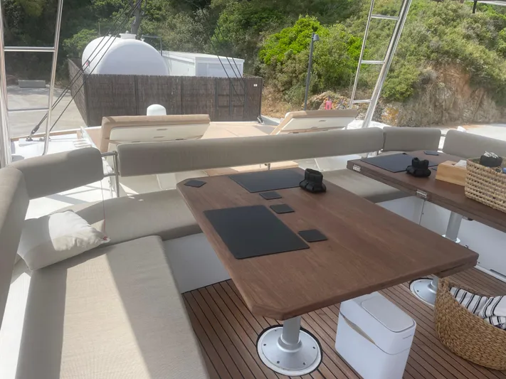  Yacht Photos Pics Luxurious 2023 Bali 5.4 yacht deck with elegant seating and wooden table, surrounded by lush greenery.